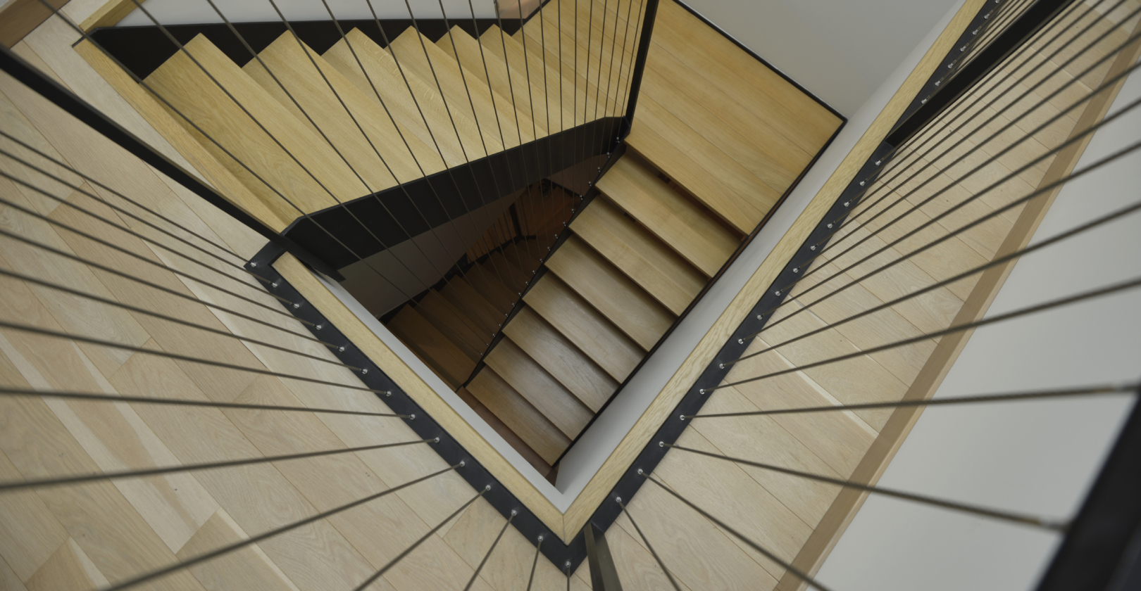 vue au coeur de l'escalier avec garde-corps inox cables tendus acier noir, marches bois, escalier double quart tournant