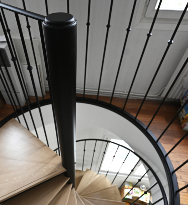 Escalier sur mesure avec fût centrale et tête de fût sur mesure en acier laqué noir mat texturé.